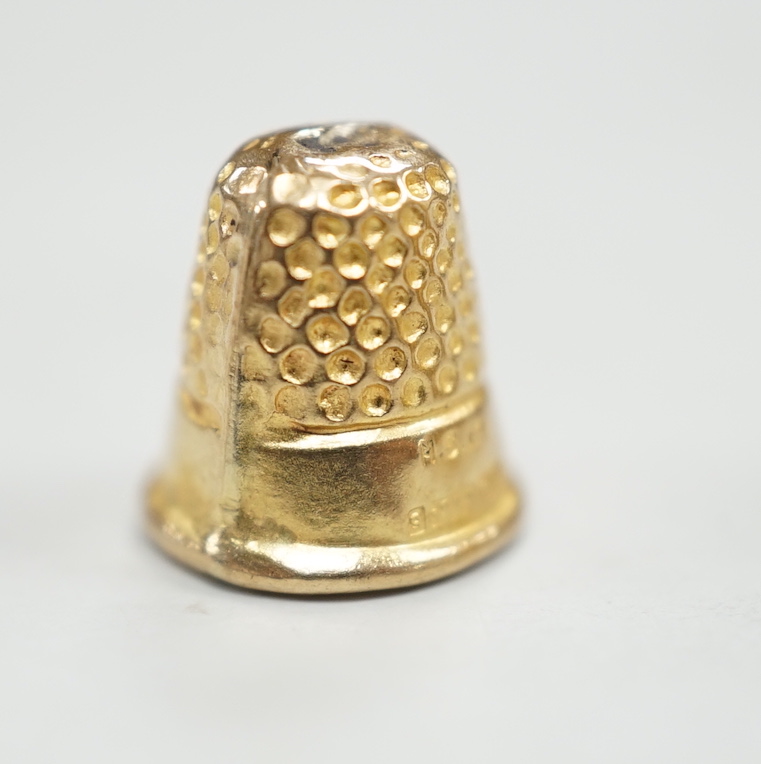 A French yellow metal (18ct poincon mark) thimble, 22mm, 5.4 grams and a tiny 1960's 9ct gold thimble, 9mm, 0.5 grams.